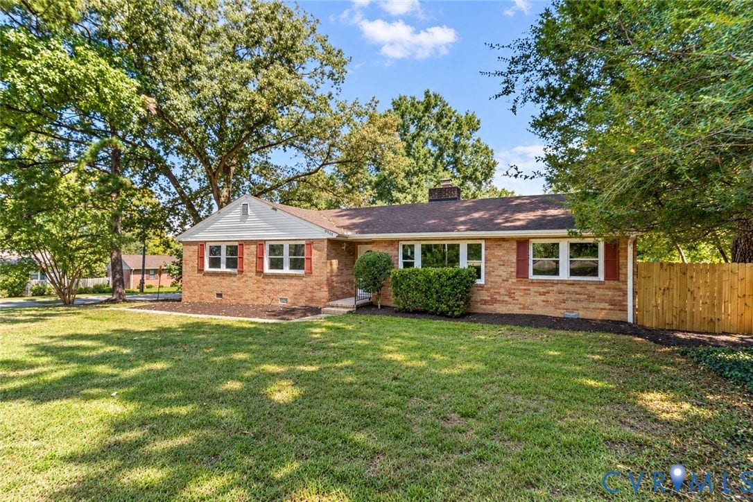 5968 Forest Hill Avenue, Westlake Hills, Richmond, VA 23225 Brick exterior with white window frames and red shutters, featuring a brown shingle roof, mature landscaping, and a wooden privacy fence