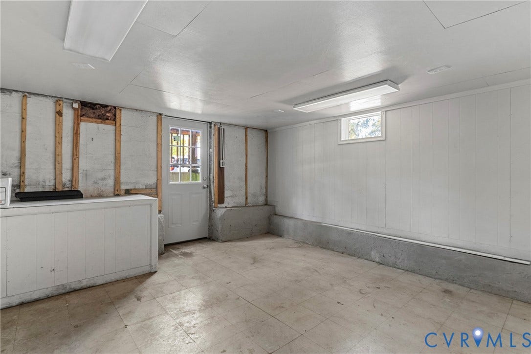 5968 Forest Hill Avenue, Westlake Hills, Richmond, VA 23225 White paneling, concrete foundation, exterior access door with window panes, window with natural light, and overhead fluorescent lighting