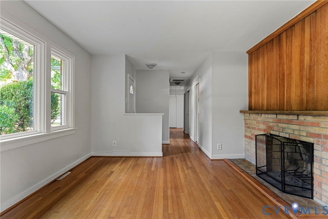 5968 Forest Hill Avenue, Westlake Hills, Richmond, VA 23225 Hardwood flooring, brick fireplace, wood paneling accent wall, multiple windows with white trim, and a hallway with closet doors