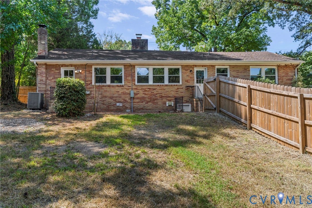 5968 Forest Hill Avenue, Westlake Hills, Richmond, VA 23225 Brick exterior with multiple windows, a wooden privacy fence, a back door with stairs, and mature trees