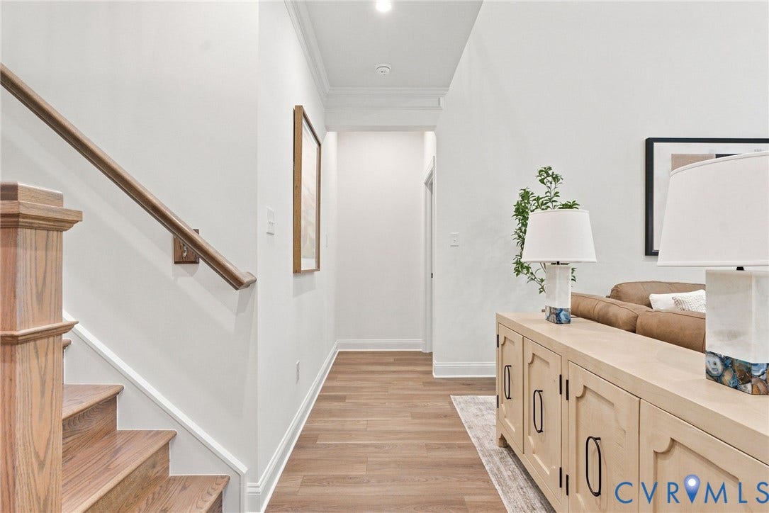 Wood-finish flooring, staircase with wood newel post and handrail, white crown molding, and recessed lighting
