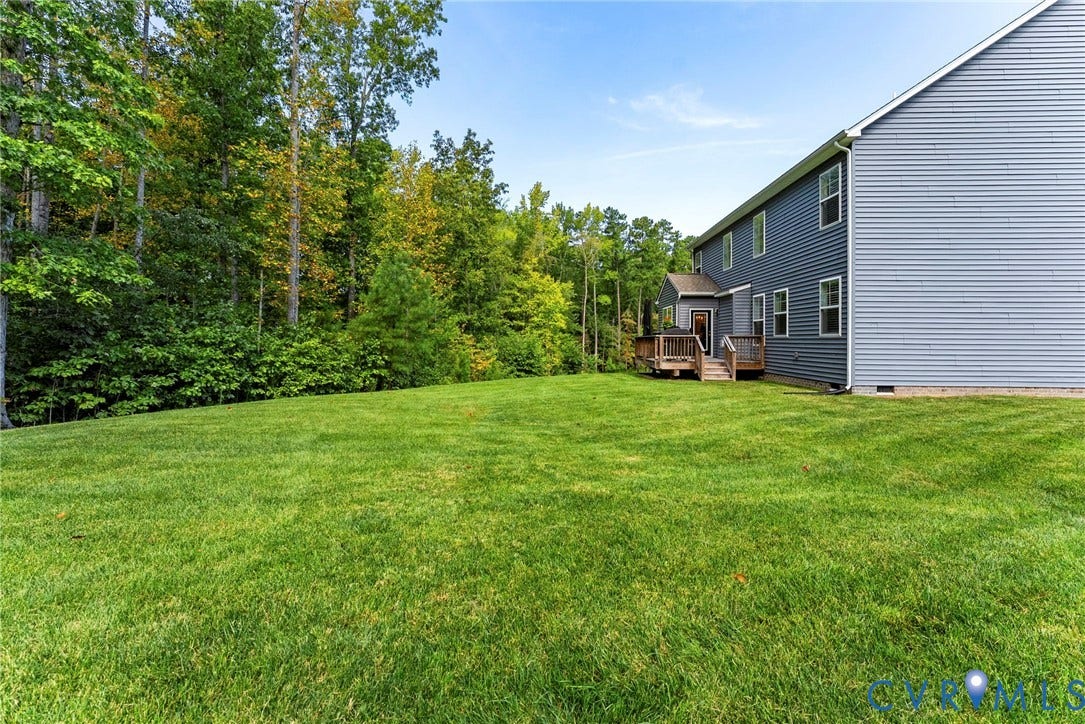 Expansive green lawn with mature trees and a multi-level rear deck
