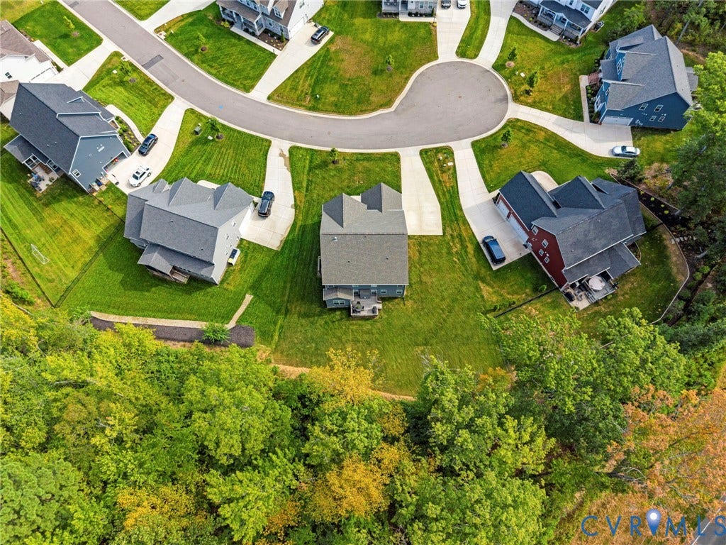 Residential property with a cul-de-sac street pattern, expansive green lawns, mature trees, and multiple detached homes