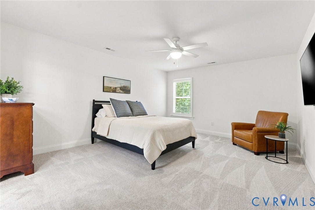 Neutral white walls, patterned carpet flooring, single window with blinds, ceiling fan with integrated lighting, and white baseboards