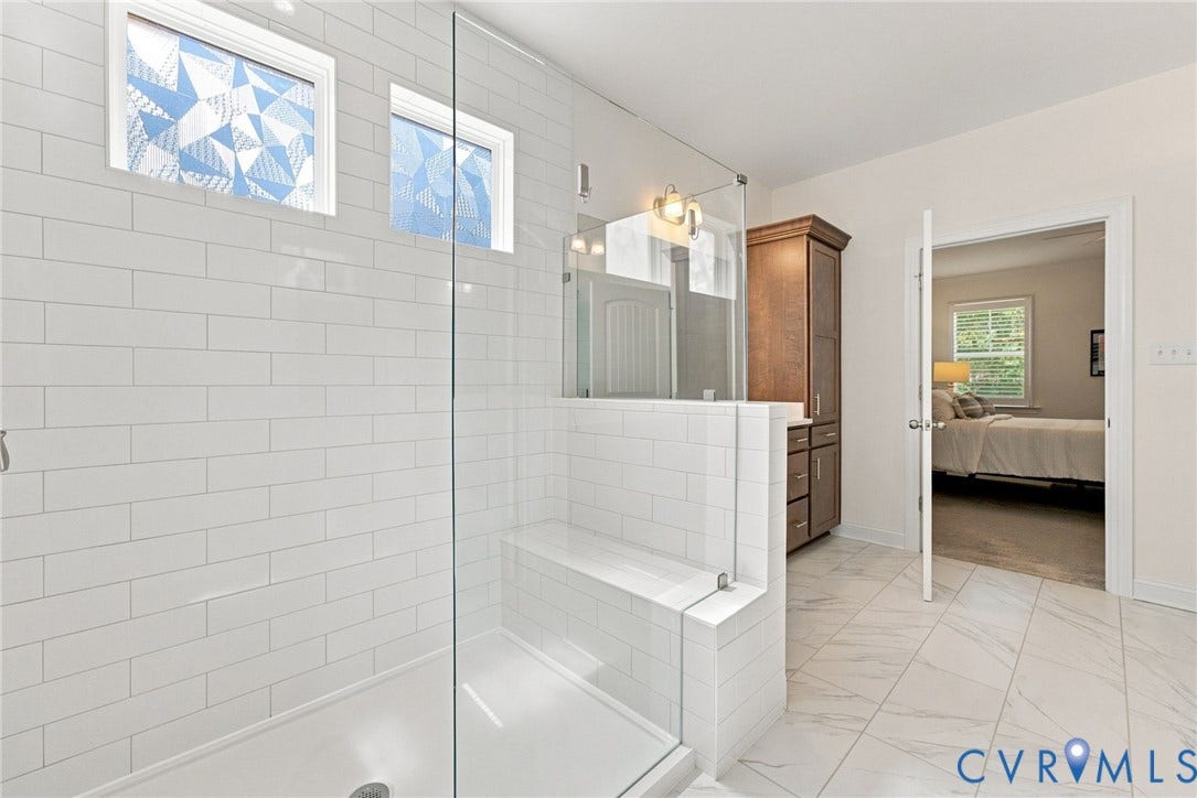 Glass-enclosed shower with white subway tile, built-in bench, and dual windows