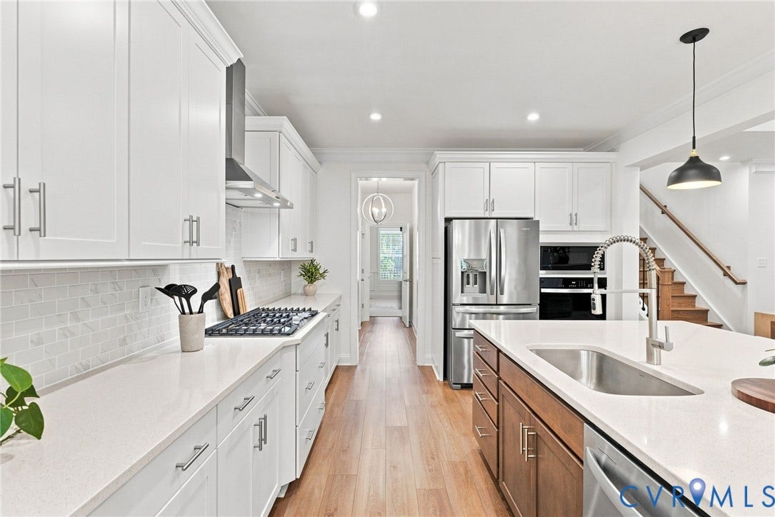 Contemporary kitchen featuring white shaker cabinetry, stainless steel appliances, a gas range, a mosaic tile backsplash, and light wood-finish flooring