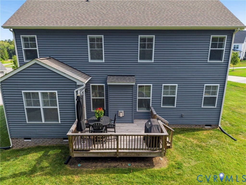 Rear exterior featuring gray siding, a wood deck, and multiple windows
