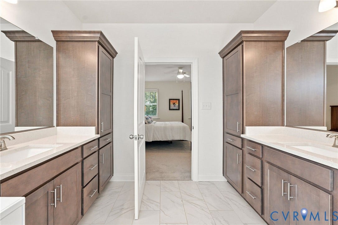 Dual vanity with white undermount sinks, stone countertops, and dark wood-finish cabinetry
