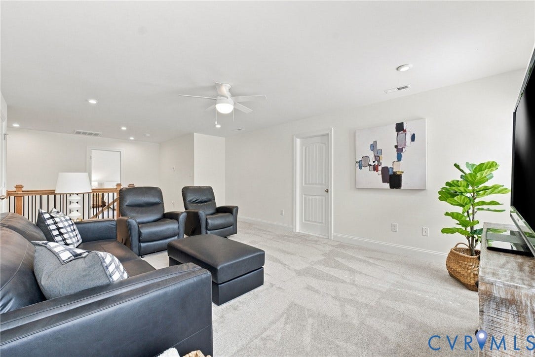 Carpeted flooring, recessed lighting, ceiling fan, white paneled door, and a wood-finish railing with white balusters