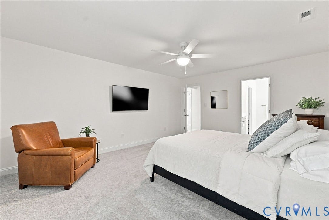 Recessed ceiling light, ceiling fan, wall-mounted television, and neutral carpet flooring