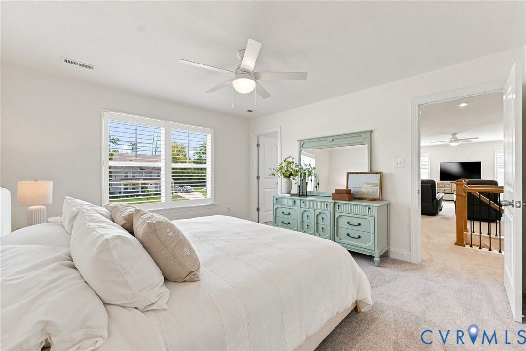 White walls with a ceiling fan light fixture, two windows with white blinds, and light-toned carpeting