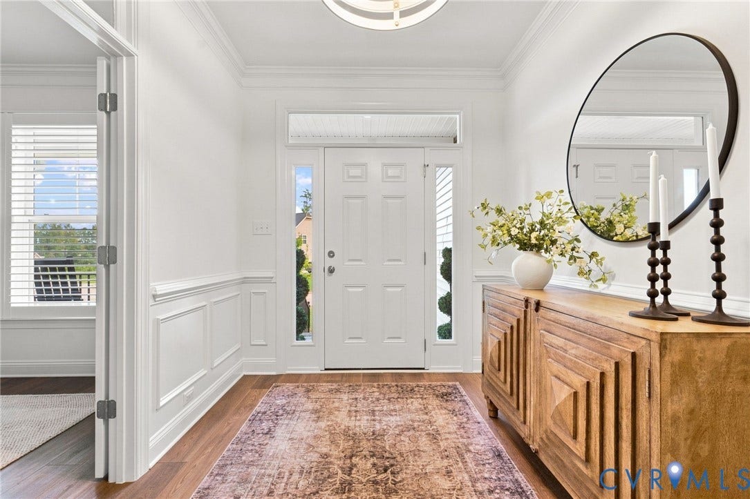 Foyer featuring wood-finish flooring, wainscoting, crown molding, a decorative ceiling fixture, and a front entry door with side lights and transom window