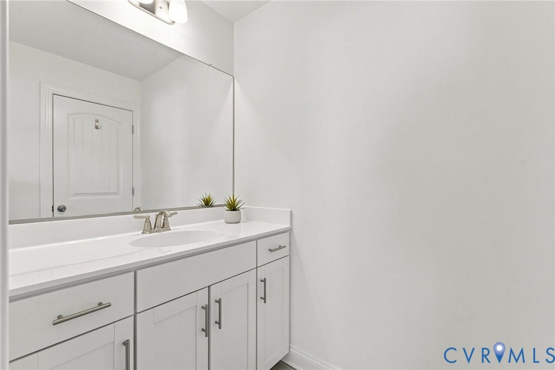 White vanity with brushed nickel hardware, integrated rectangular sink, and white countertop