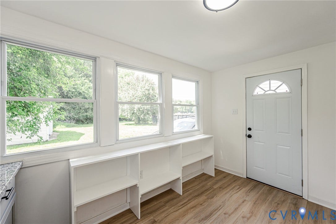 4008 River Road, Chesterfield, VA 23803 White paneled entry door with an arched transom window, wood-finish flooring, and built-in shelving below multiple windows