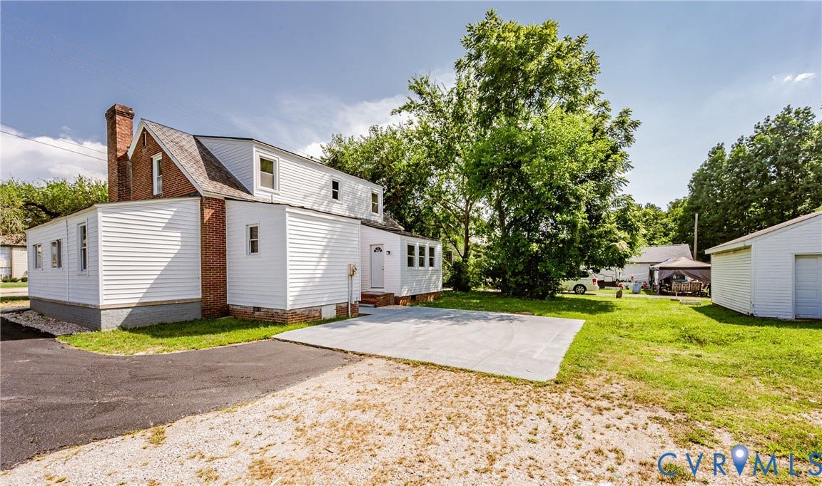 4008 River Road, Chesterfield, VA 23803 White siding exterior with a brick chimney, a paved driveway, and a concrete pad