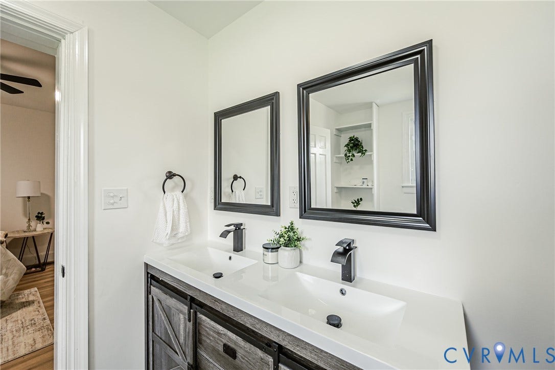 4008 River Road, Chesterfield, VA 23803 Dual rectangular undermount sinks, white countertop, dark wood-finish vanity with barn door style fronts, and black framed mirrors