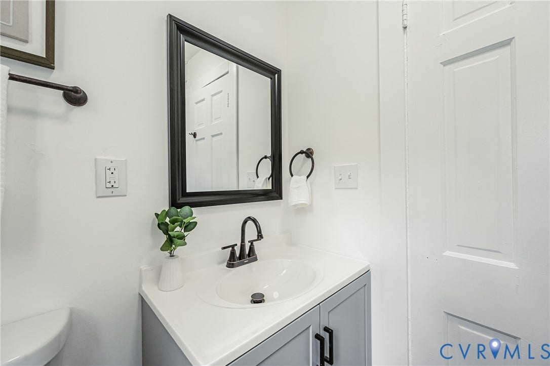 4008 River Road, Chesterfield, VA 23803 Vanity with a white countertop and integrated sink, framed mirror, and two-door cabinet with black hardware