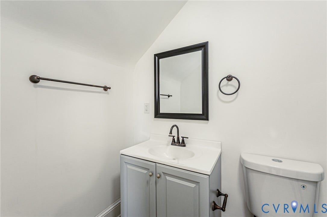 4008 River Road, Chesterfield, VA 23803 White vanity with an integrated sink, dark bronze-finish faucet, and a framed mirror