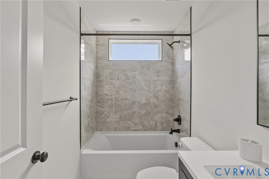 2004 Newbourne Street, Richmond, VA 23223 Bathtub with tile surround, a built-in window, and matte black fixtures
