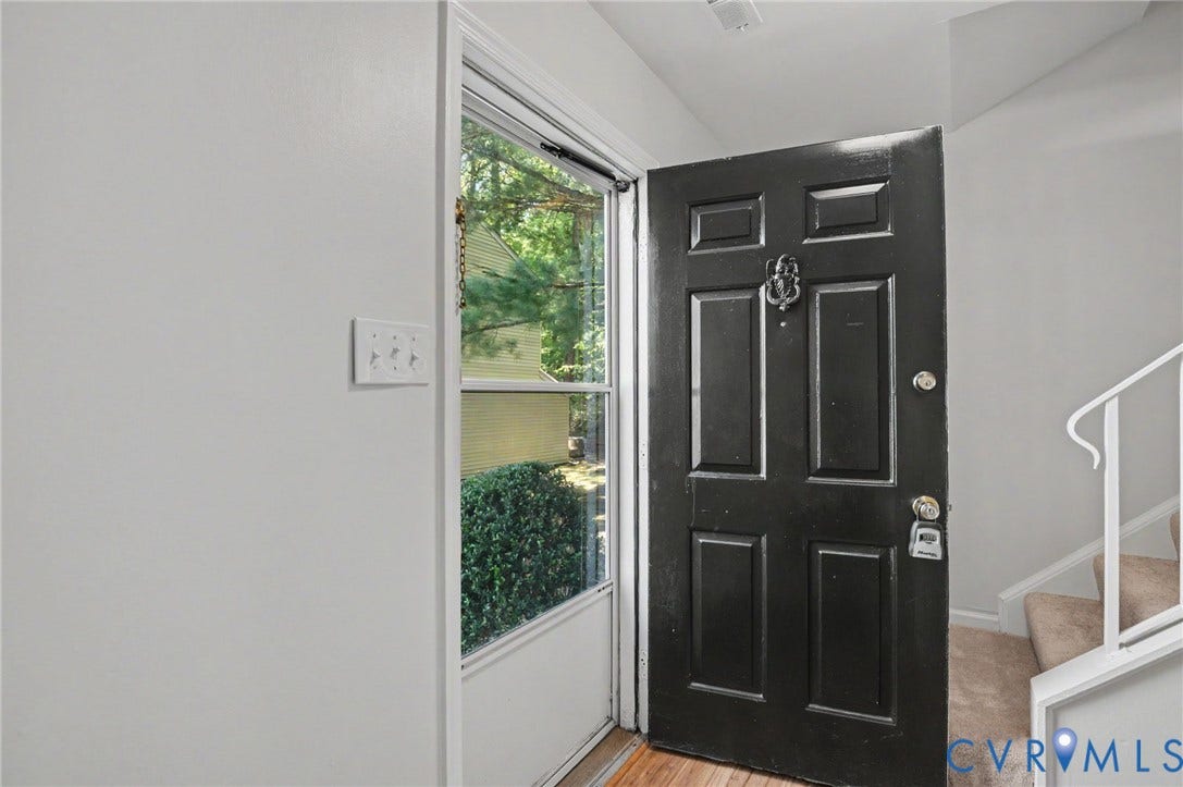 1555 Skirmish Run Drive, #1555, Henrico, VA 23228 Black paneled entry door with decorative knocker, wood-finish flooring, and white painted walls