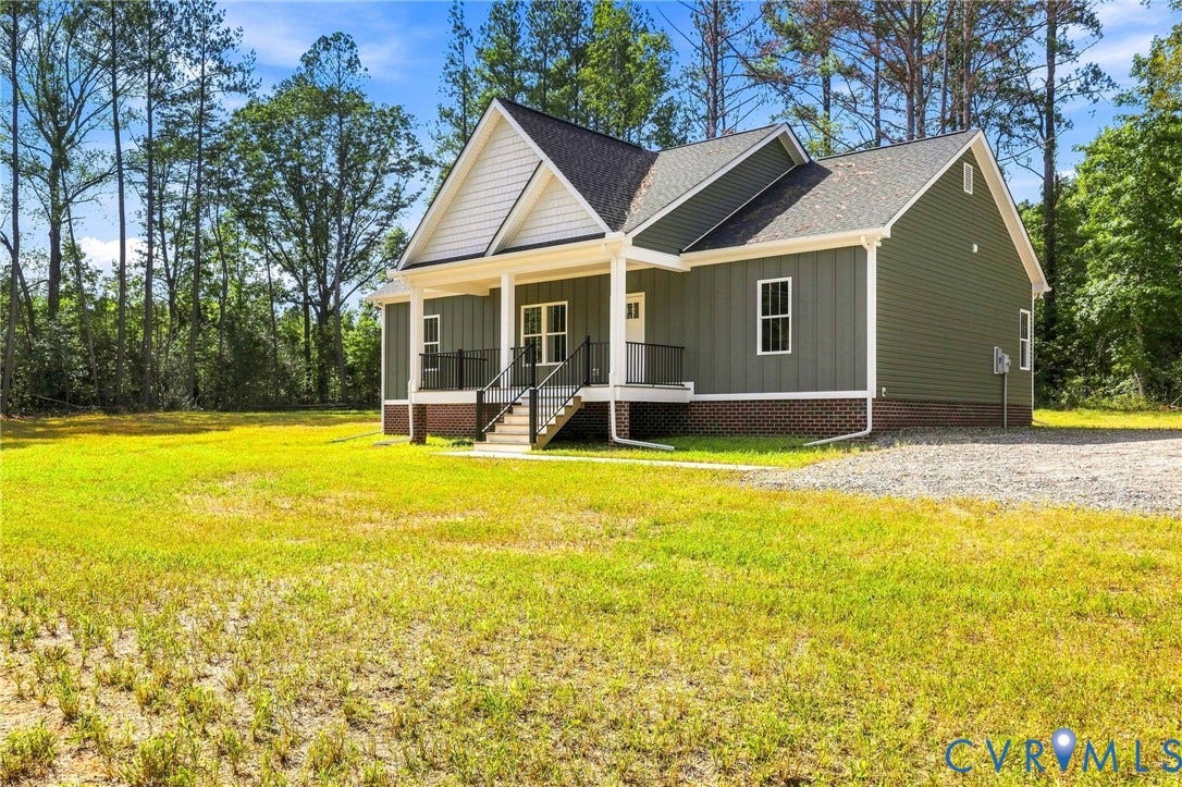 3289 Cumberland Road, Cumberland, VA 23040 Craftsman-style home featuring a covered front porch with black railings, a gravel driveway, and a deep green exterior with white trim