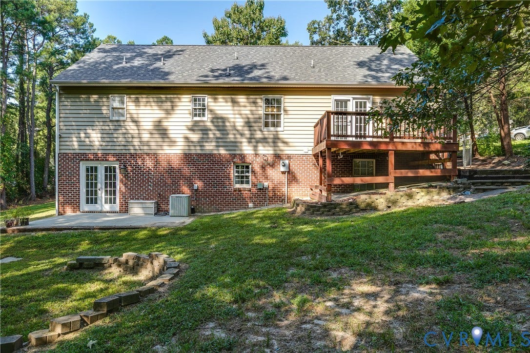3207 Ludgate Road, Chester, VA 23831 Expansive rear exterior featuring brick and siding finishes, a lower-level patio, an upper-level wooden deck with railings, and a terraced yard with integrated steps
