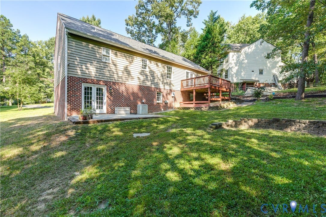 3207 Ludgate Road, Chester, VA 23831 Brick and siding exterior with a multi-level wood deck, a ground-level patio, and a sloped lawn with mature trees