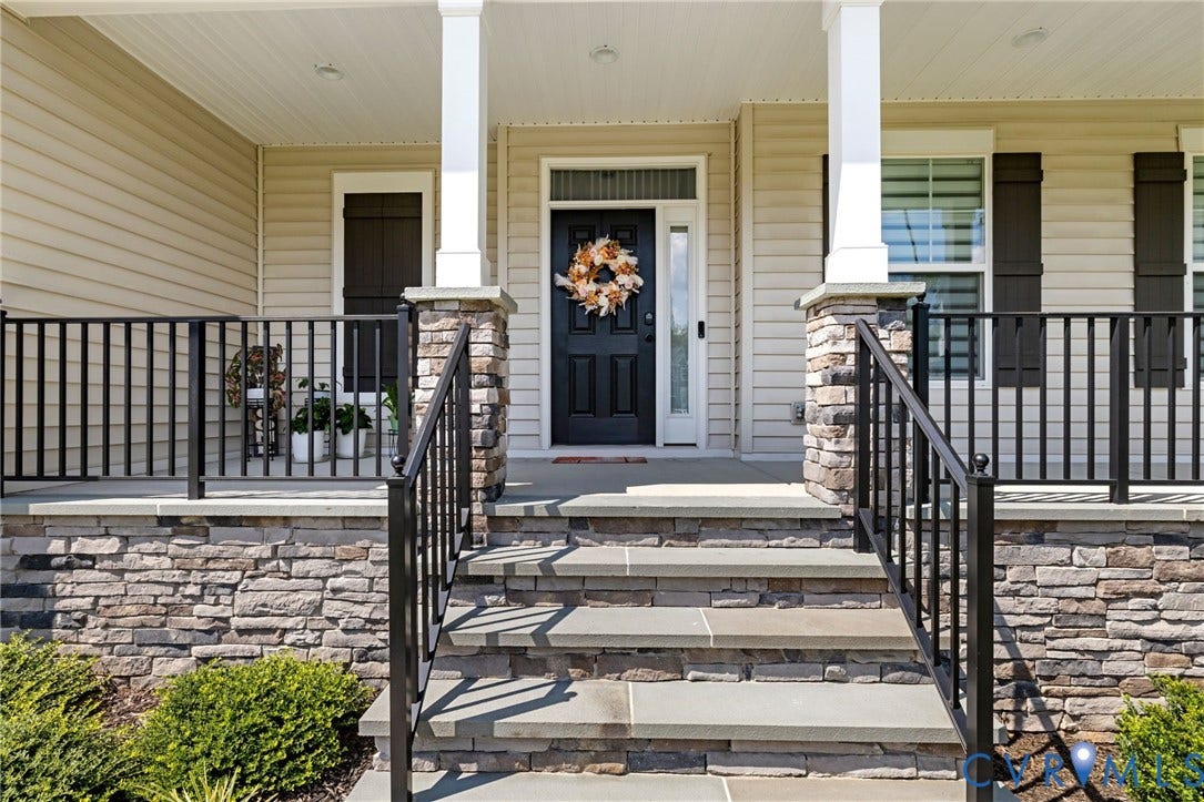 Front porch featuring stacked stone accents, stone steps, black railings, and a solid black entry door
