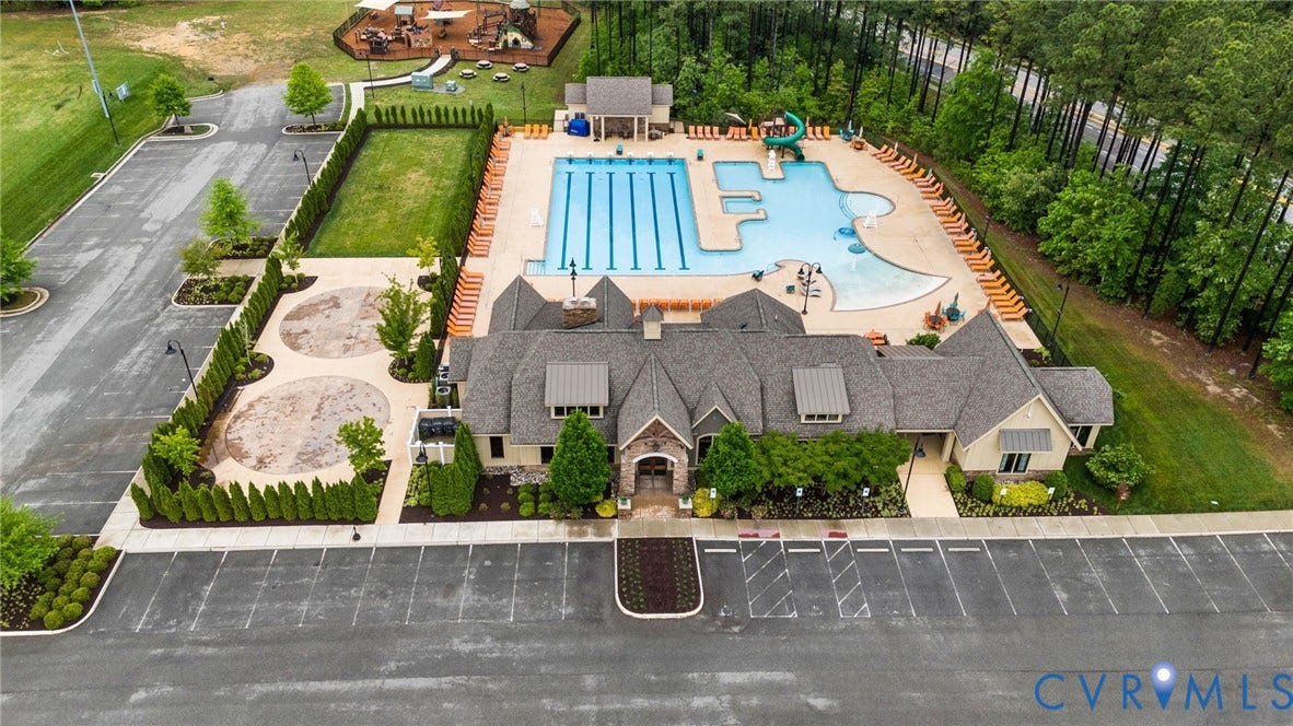 Expansive clubhouse with stone and siding exterior, multiple pools, and a separate aquatic slide area