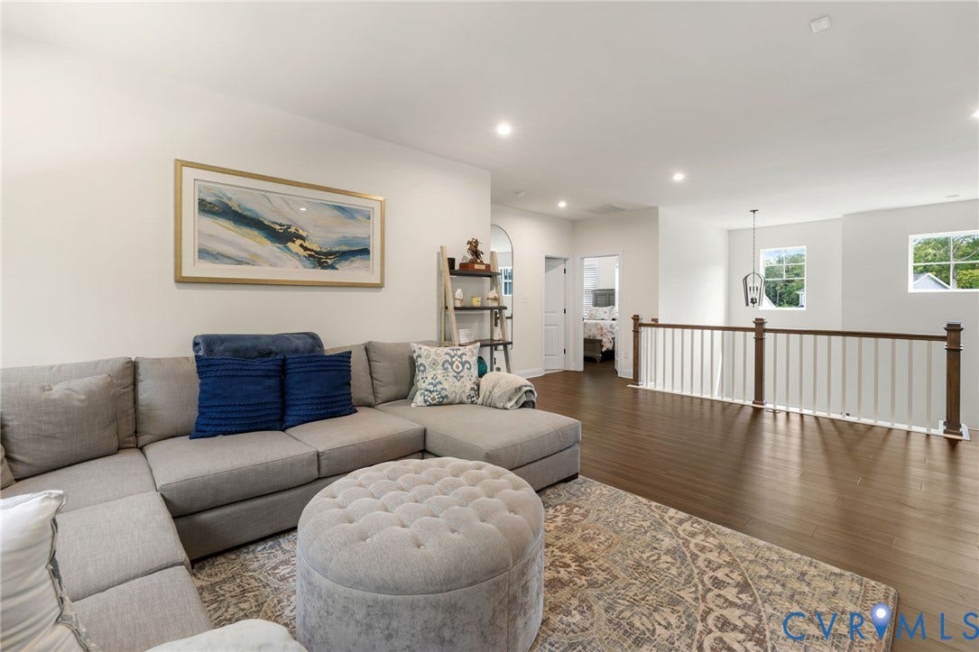 Open concept space featuring wood-finish flooring, white walls, recessed lighting, and a white and wood-tone railing
