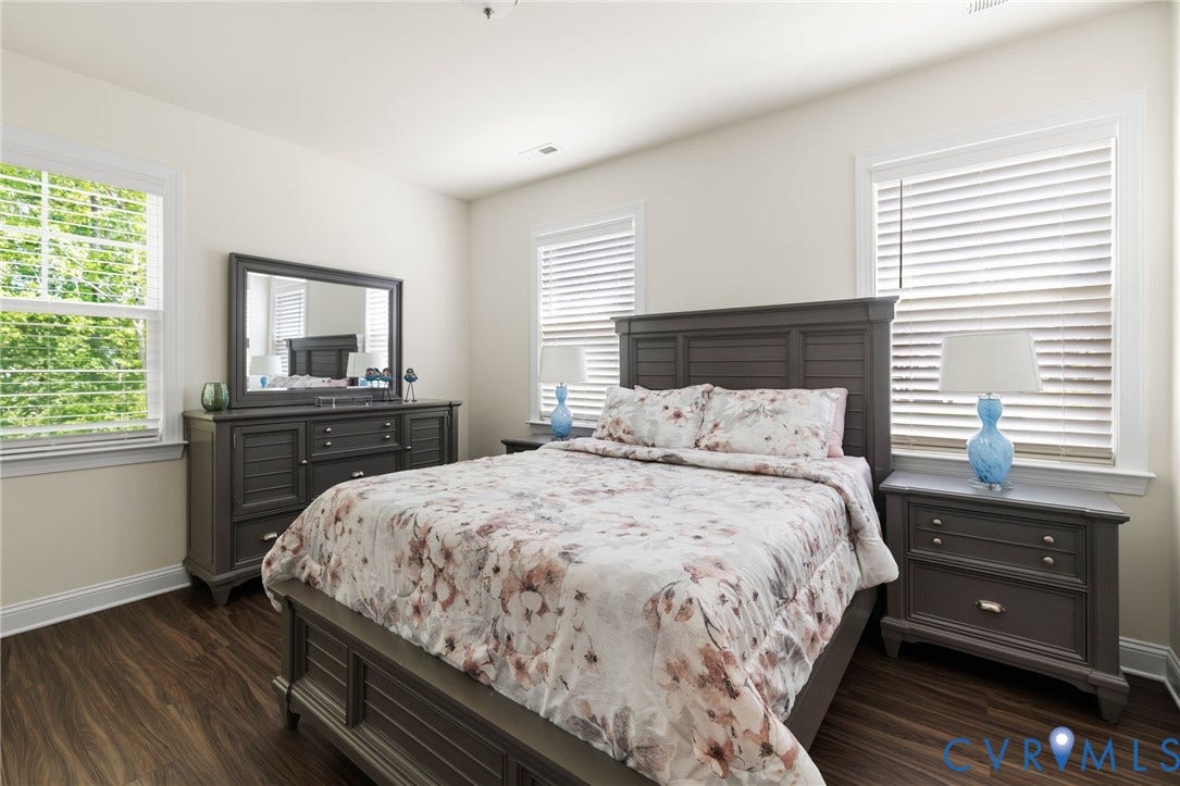 Two windows with horizontal blinds, wood-finish flooring, and light-toned walls