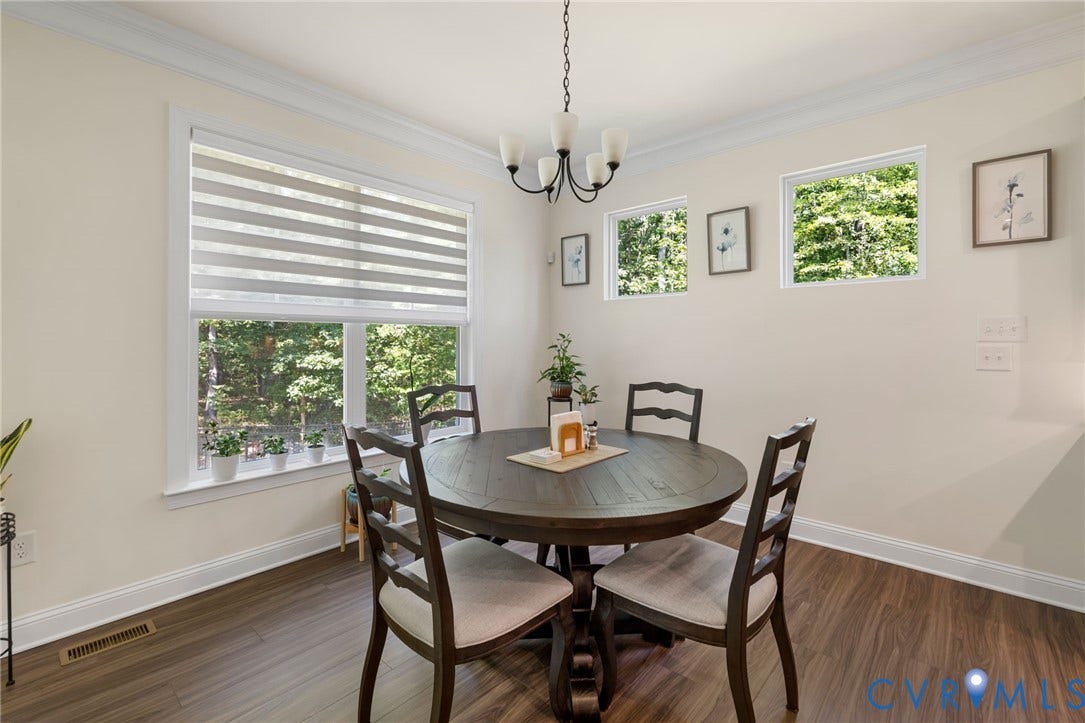 Wood-finish flooring, crown molding, white trim, and multiple windows with roller blinds