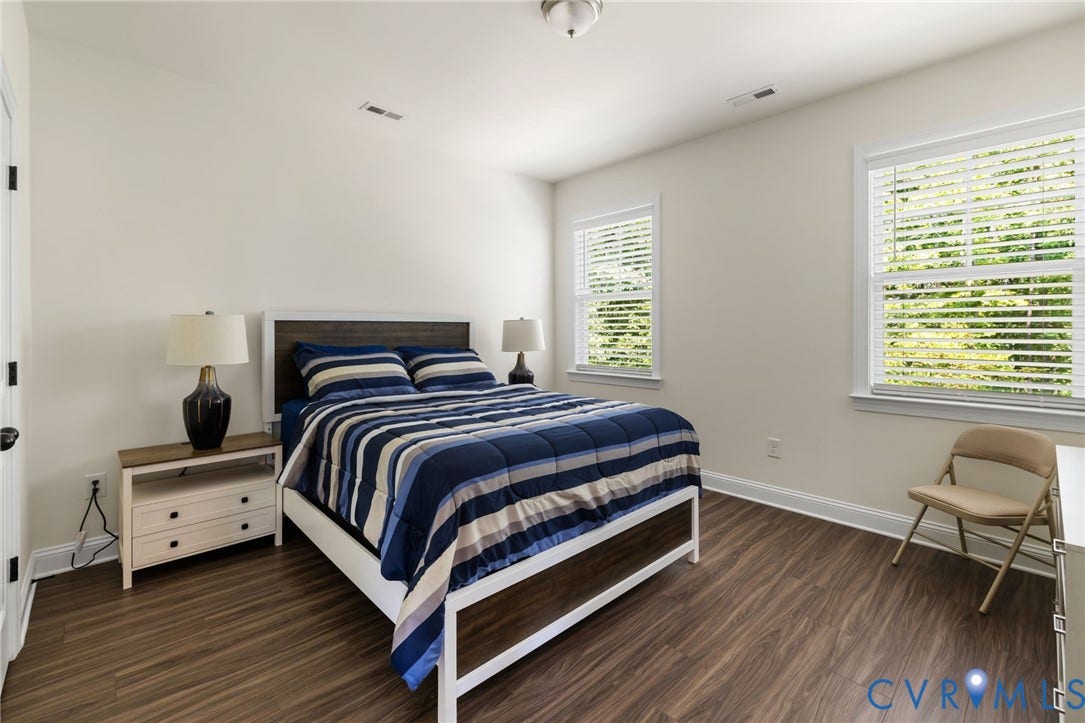 Wood-finish flooring, white trim, and two windows with blinds