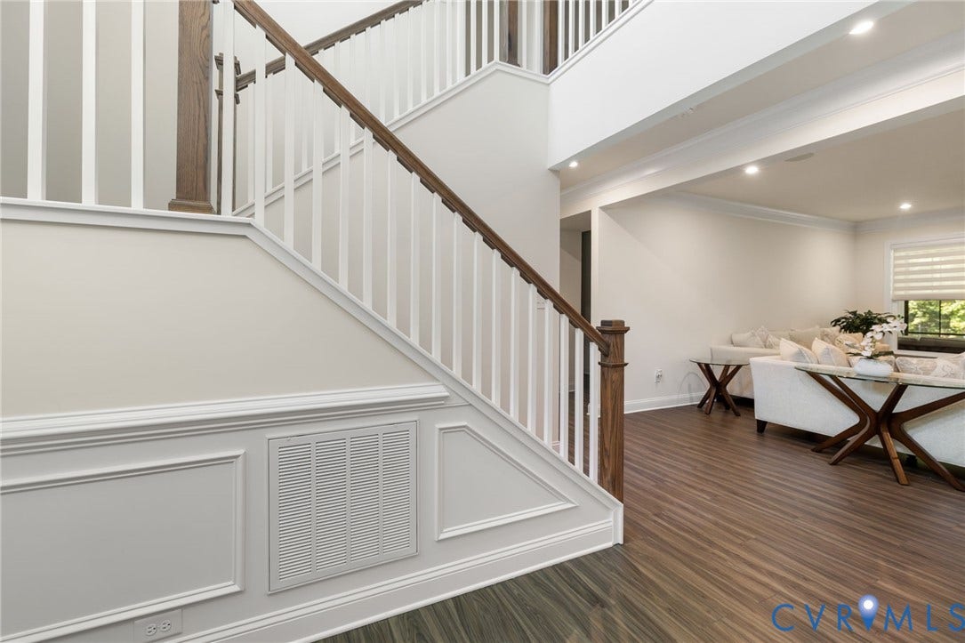 Wood-finish flooring, staircase with wood handrail, white balusters, and wainscoting, recessed lighting, and crown molding