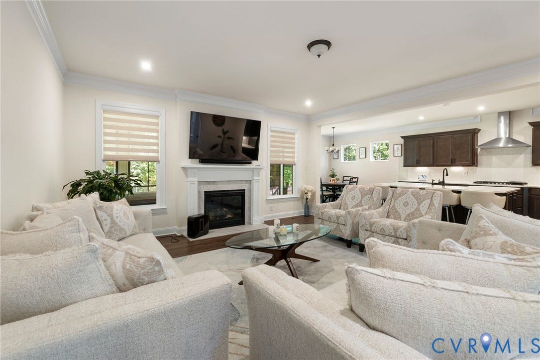 Living area featuring wood-finish flooring, a white mantel fireplace, and recessed lighting