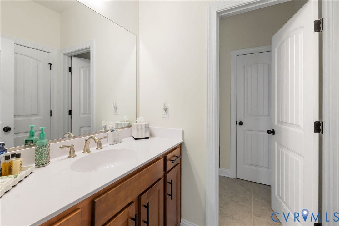 Vanity with wood-finish cabinetry, countertop with integrated sink, and brushed nickel faucet