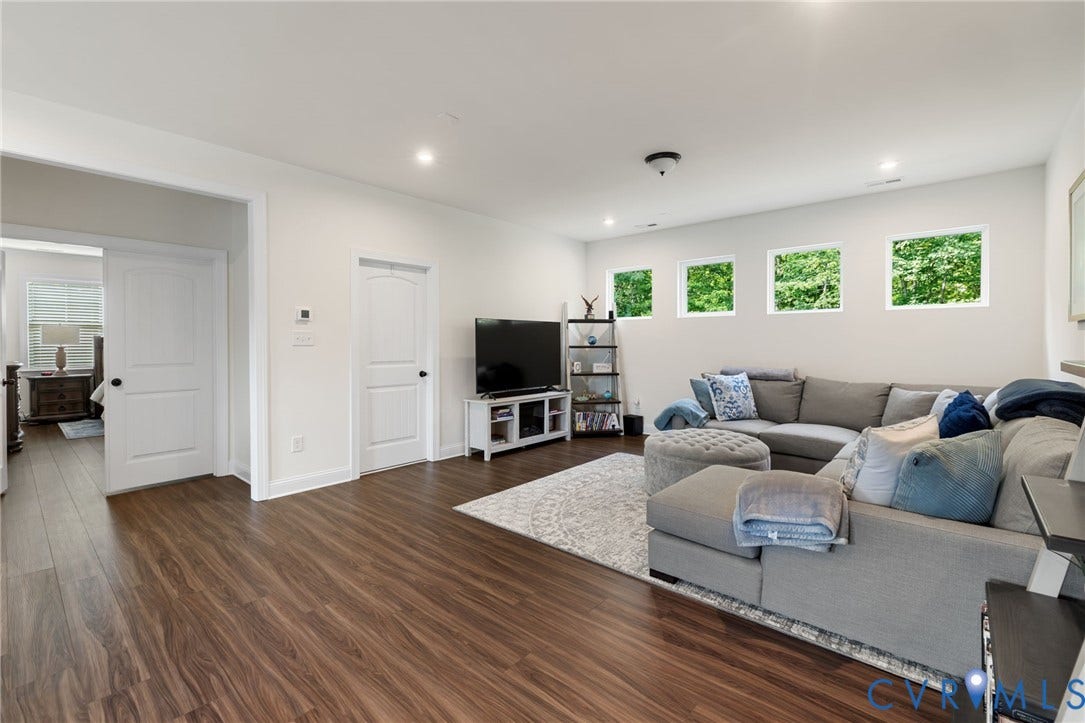 Spacious living area featuring wood-finish flooring, recessed lighting, and multiple windows