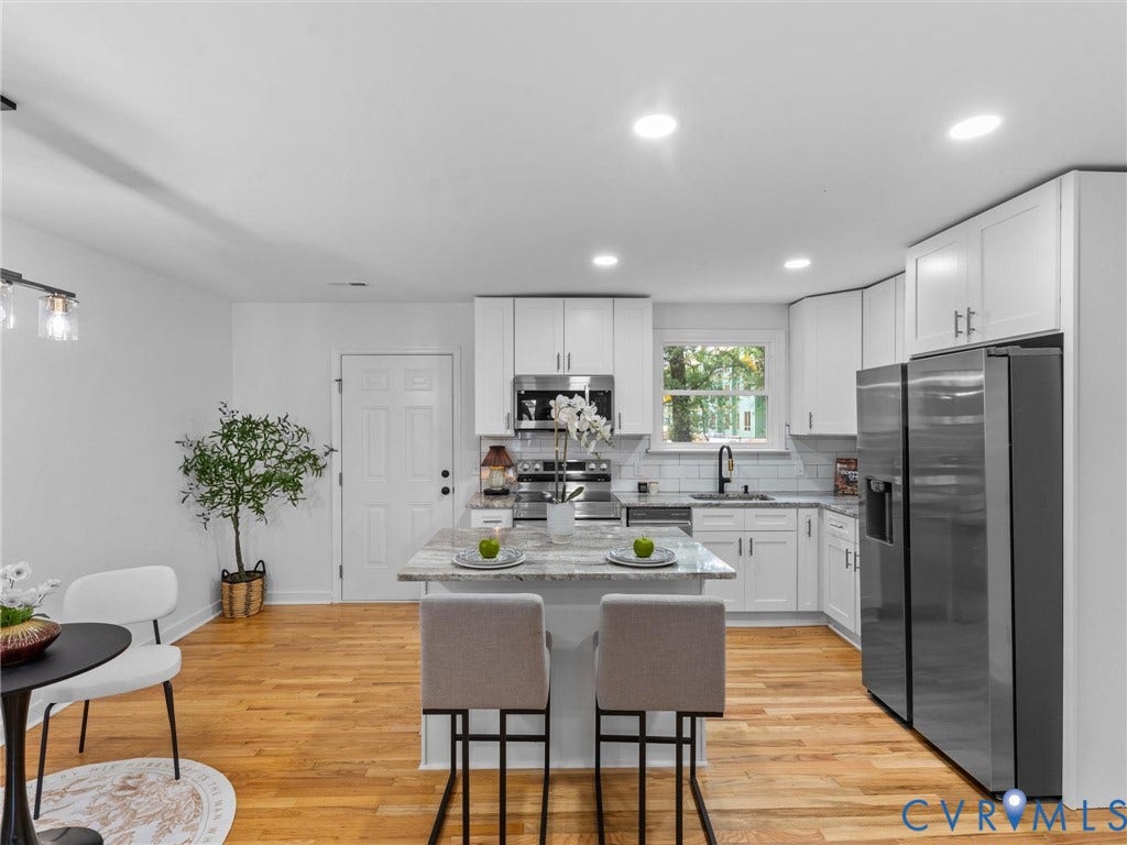 3626 Reynolds Road, Richmond, VA 23223 Kitchen with wood-finish flooring, white cabinetry, a central island with countertop seating, stainless steel appliances, and recessed lighting