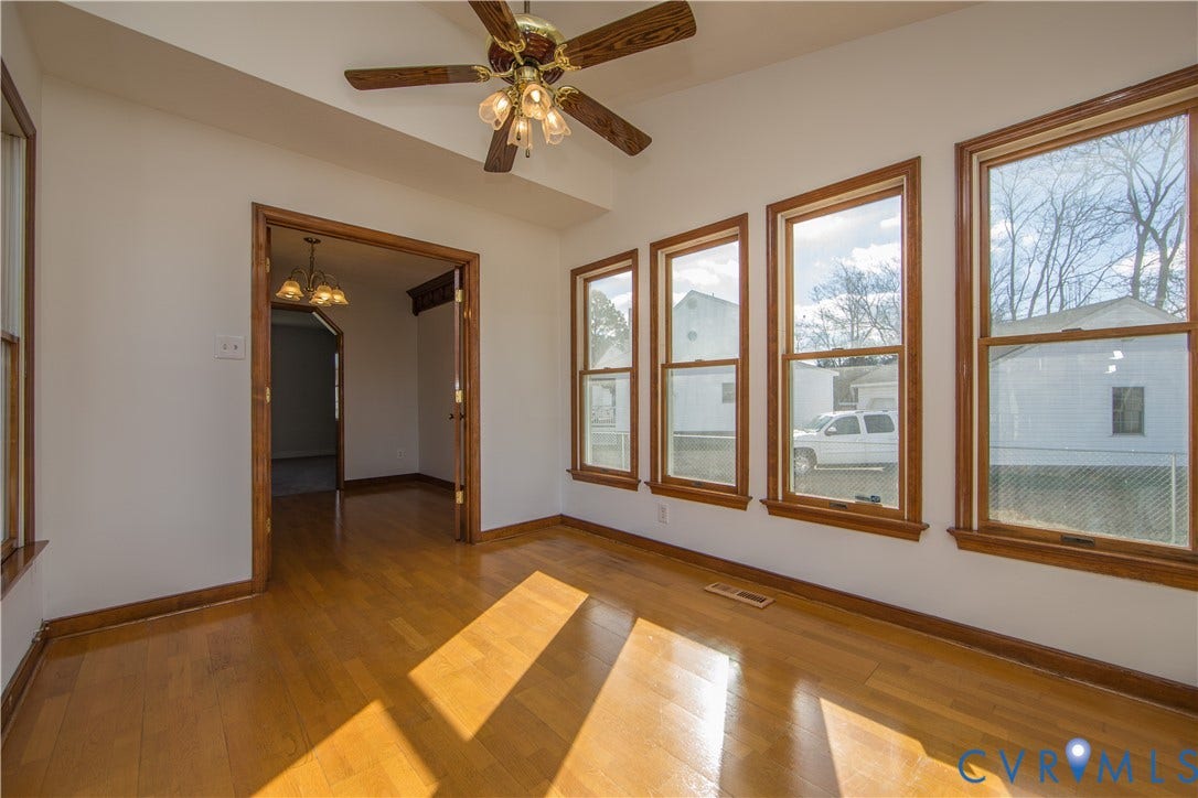19224 Maurer Lane, Colonial Heights, VA 23834 Hardwood flooring throughout, multiple large windows with wood trim, ceiling fan with integrated lighting, and an open doorway leading to an additional space with a chandelier