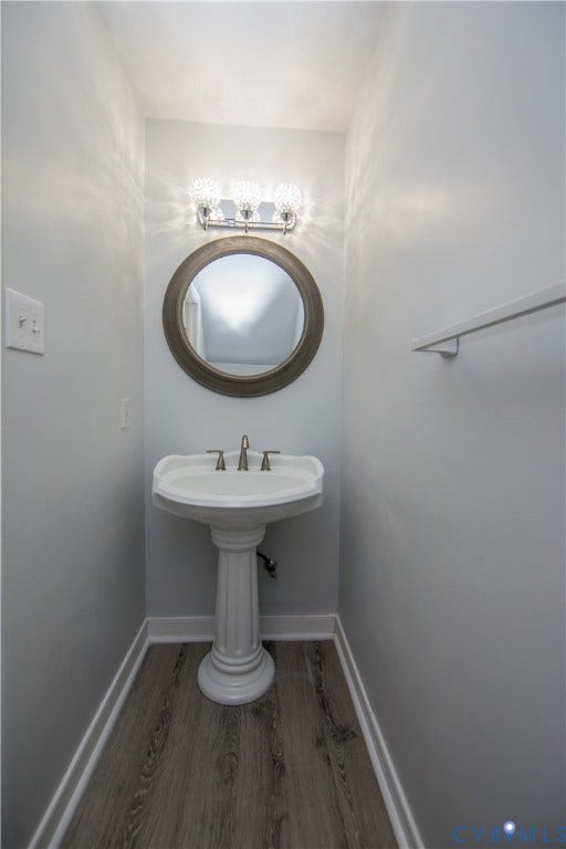 19224 Maurer Lane, Colonial Heights, VA 23834 Pedestal sink with brushed nickel faucet, round framed mirror, three-light vanity fixture, and wood-finish flooring