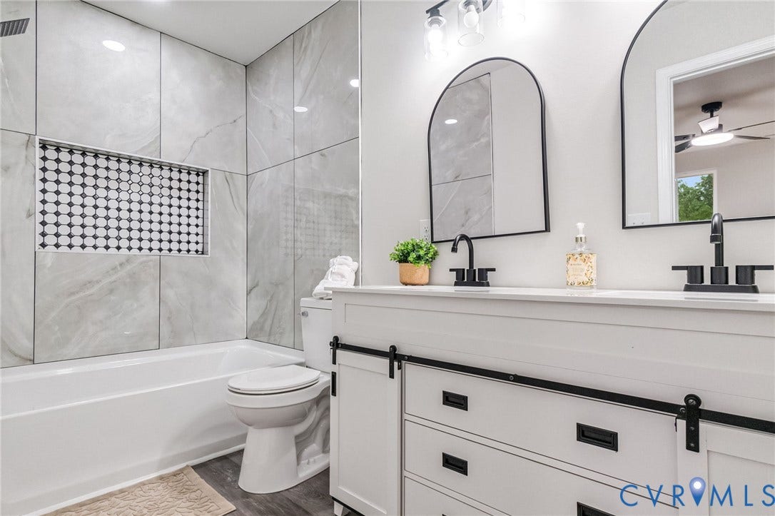 White double vanity with a quartz countertop, dual matte black faucets, and arch-top mirrors