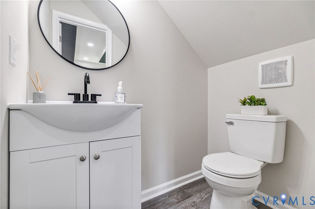 White vanity with integrated sink, matte black faucet, and wood-finish flooring