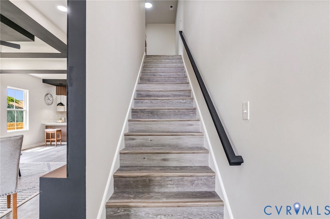 Wood-finish stair treads with white risers and a black handrail