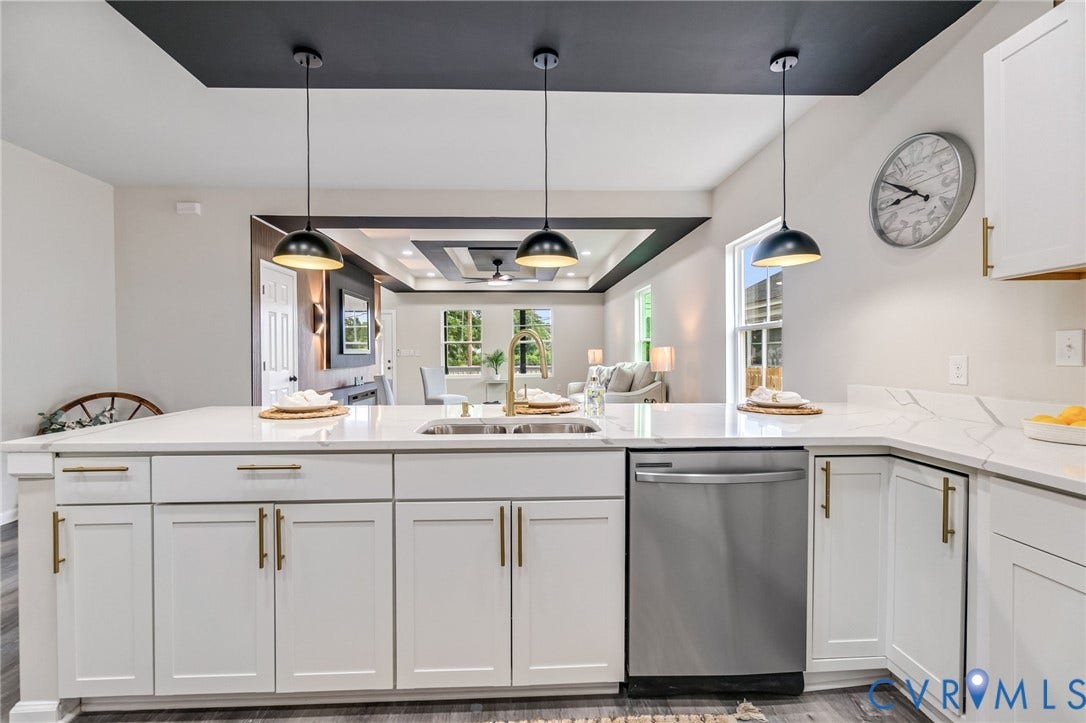 Kitchen island with white shaker cabinetry, gold-finish hardware, and a stainless steel dishwasher