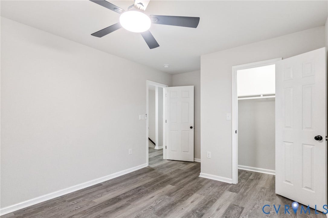Wood-finish flooring, white walls, and a ceiling fan with integrated lighting