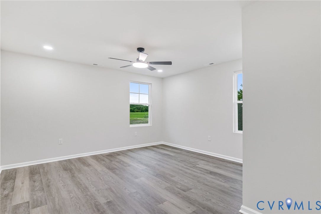 Recessed ceiling lighting, a modern ceiling fan, two windows, and wood-finish flooring