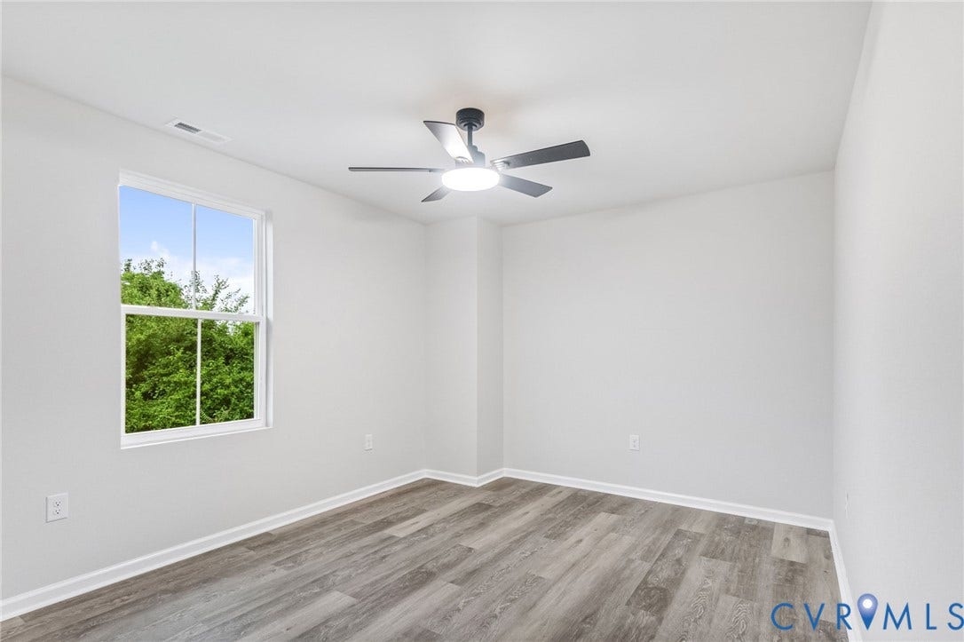 Light gray wood-finish flooring, white walls, and a modern ceiling fan with integrated lighting