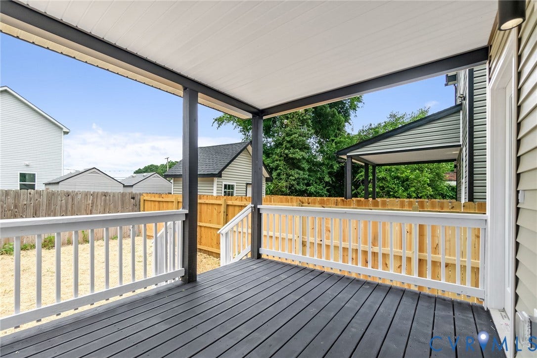 Covered back porch with dark-stained wood-finish decking and white railings