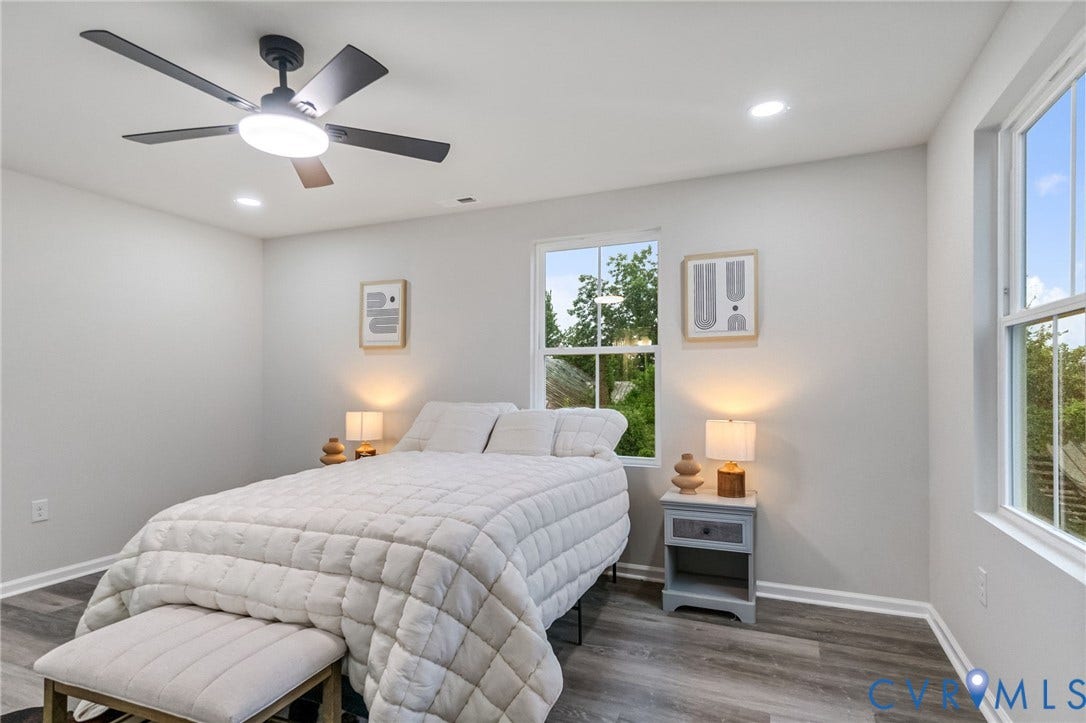 Recessed lighting, wood-finish flooring, and multiple windows providing ambient light