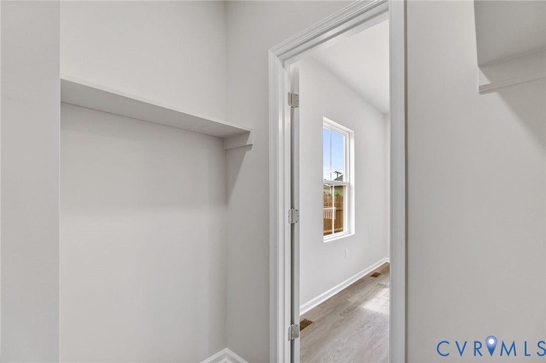 Built-in shelving, white painted walls, white trim, wood-finish flooring, and a double-hung window